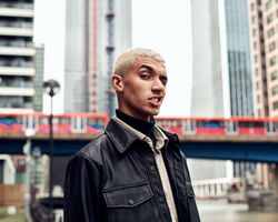 Young man making inquisitive facial expression with city in background