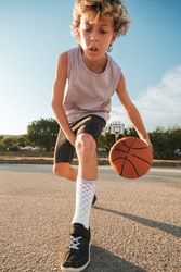Concentrated boy dribbling basketball on sports ground