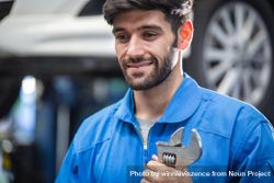 Happy male mechanic holding wrench at auto garage 43Kyr4