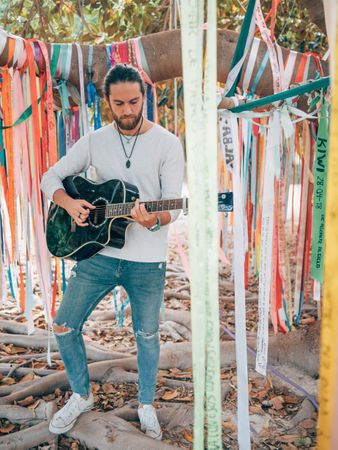 Man playing guitar under decorated tree
