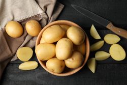 Top view of bowl of potatoes with potato wedges on dark kitchen counter