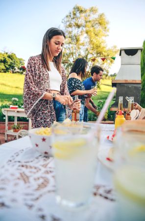 Woman opening beer bottle in summer barbecue