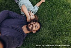 Man lying on grass in a park with his son 5a37ab