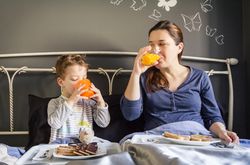 Mother and son having breakfast in bed
