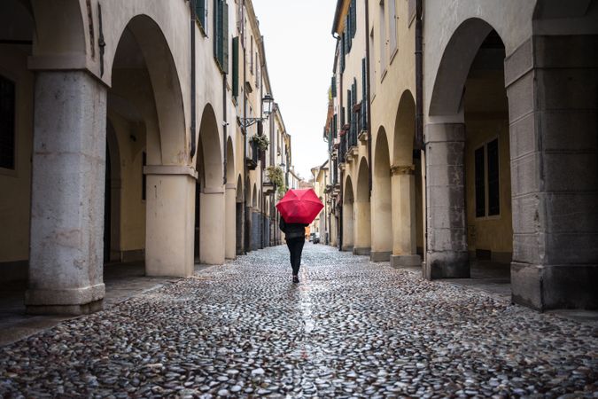 Tourist with umbrella walking at city street on rainy weather