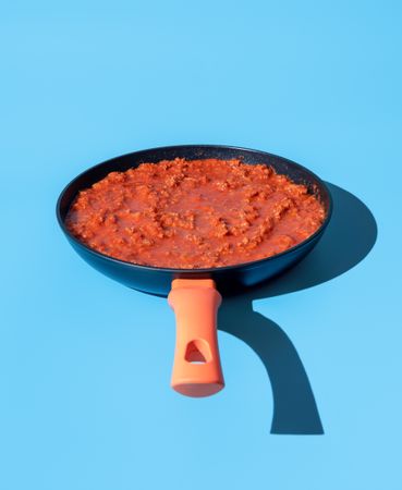 Bolognese sauce in a pan isolated on a blue background