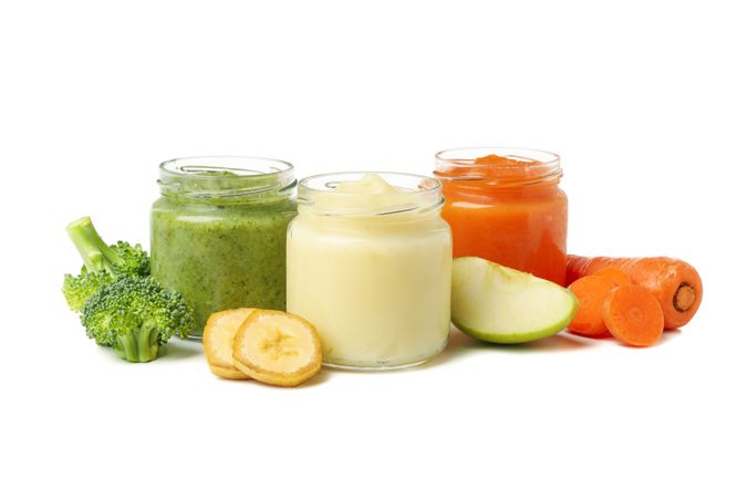 Glass jars with healthy baby food isolated on plain background
