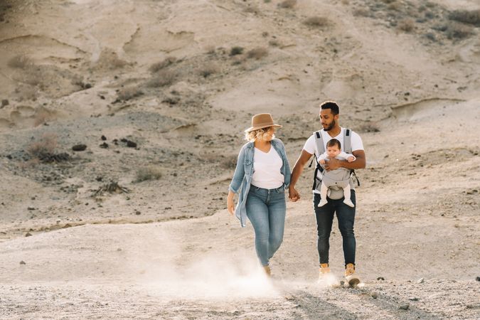 Diverse parents dancing while walking with baby