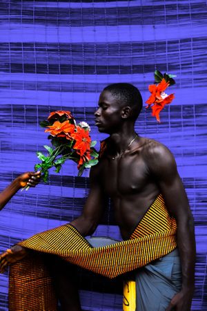 Topless man being handed a bouquet of flower