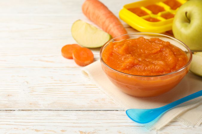 Composition with baby food on plain wooden background