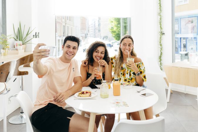 Man taking selfie of friends in cafe