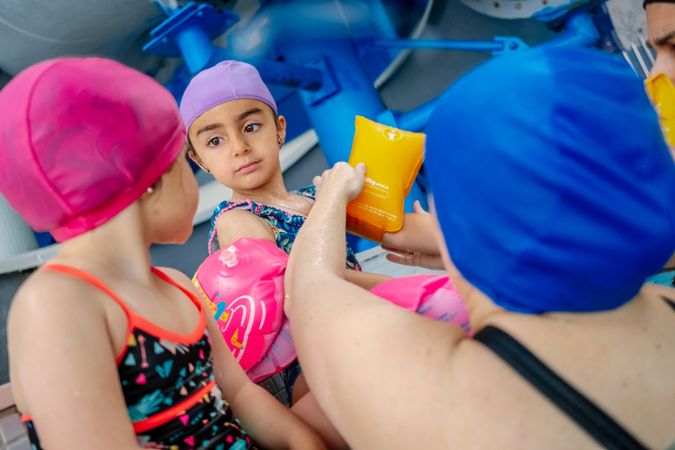 Mother putting water wings on girl