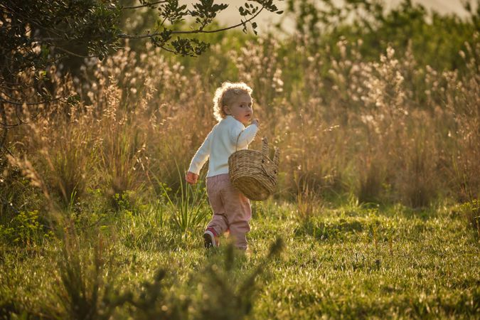 Cute girl with basket walking in summer garden
