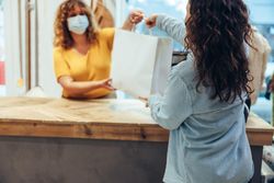 Store owner and shopper wearing protective face masks