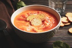 Bowl of cosy pumpkin soup on table with glass of water