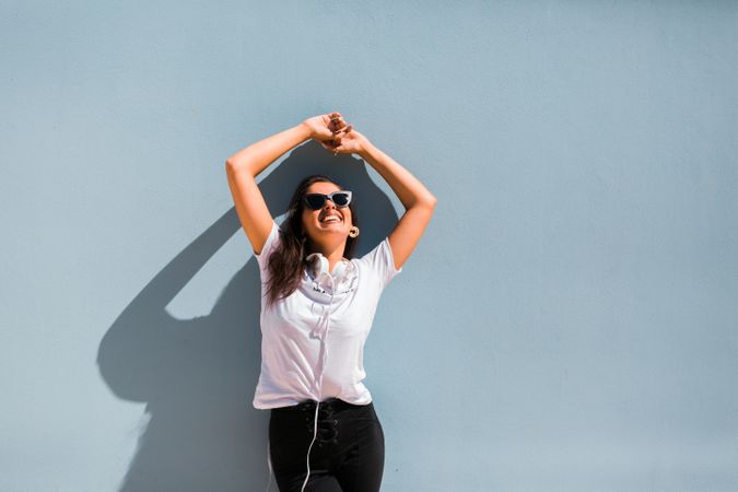Cheerful casual woman in sunglasses standing on city street
