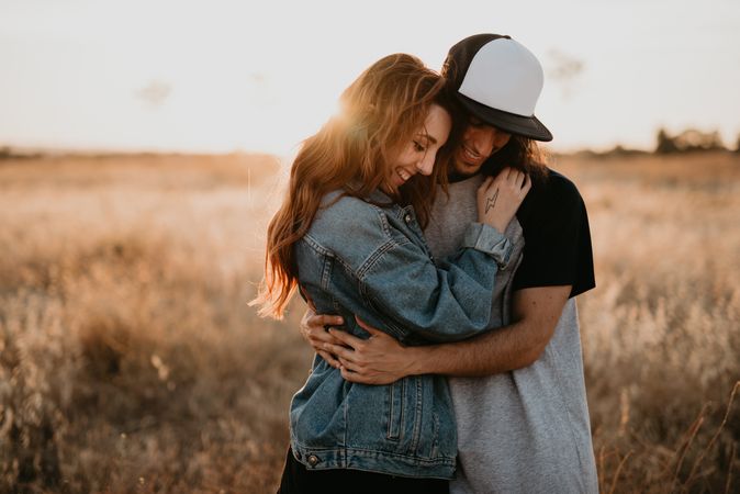 Hipster couple bonding on field in sunlight