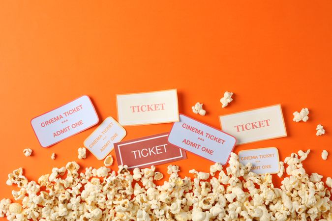 Flat lay composition with popcorn and tickets on orange background, copy space