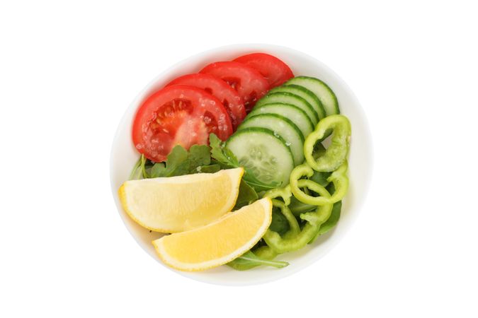 Plate with fresh vegetables slices isolated on plain background
