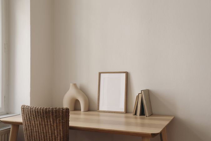 Blank picture frame mockup on wooden table, desk with rattan chair