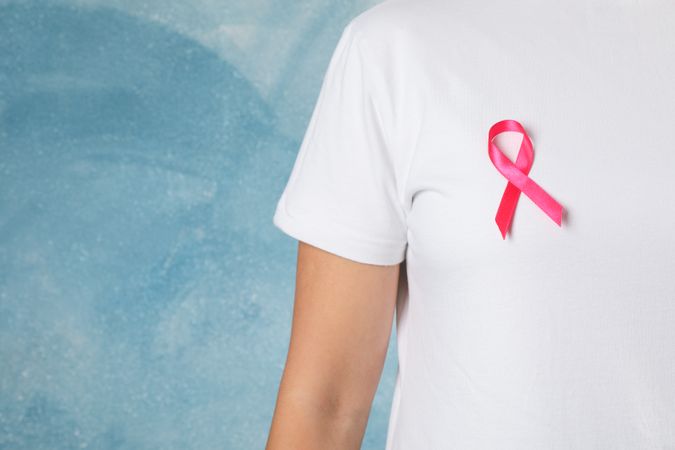Person in t-shirt with awareness ribbon against blue background