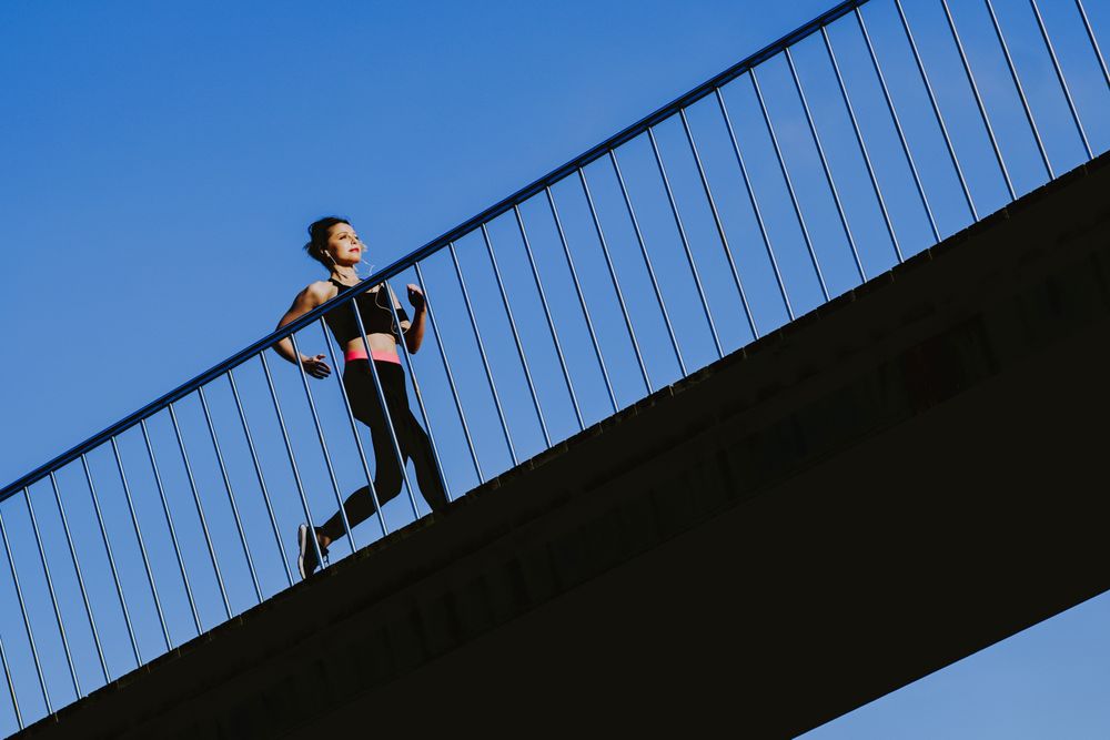 Woman running on walkway in sunny day with blue sky