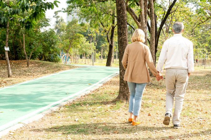Man and woman holding hand and walking at park