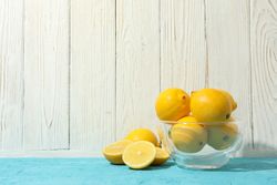 Bowl with lemons on blue table. Ripe fruit