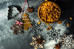 Top view of flour on counter with Christmas cookies, ingredients and snow flakes