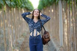A Joyful Young Woman is Posing Happily in a Lush Vineyard Surrounded by Natures Beauty