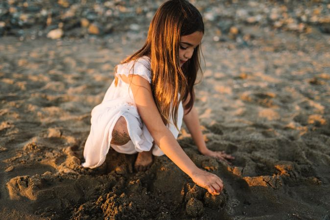 Adorable girl playing with sand on beach