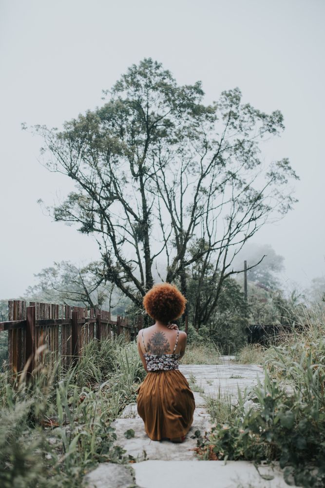 Back view of woman crouching on floor near tree