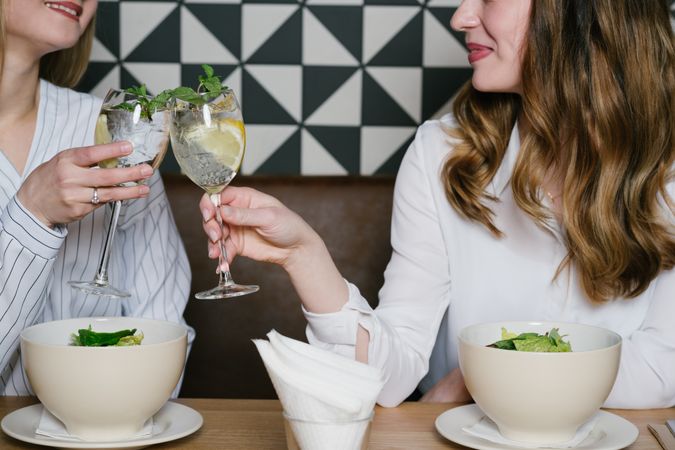 Cheerful friends clinking glasses in cafe