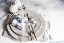 Wrapped Christmas present with ornaments on table setting