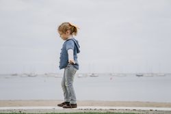 Girl balancing on border near sea