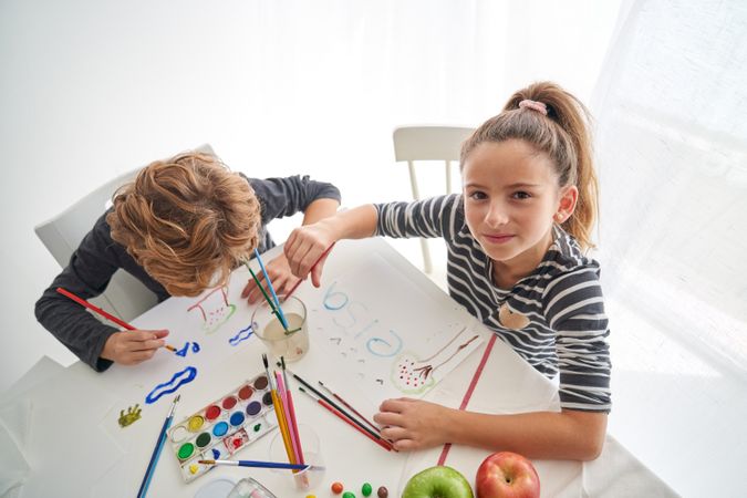 Positive girl painting near boy