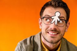 Smiling man with funny paper toy on eyeglasses