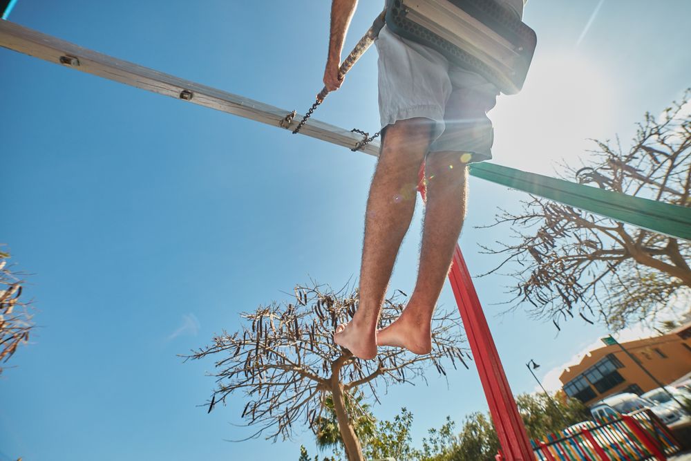 Man swinging on playground in sunlight