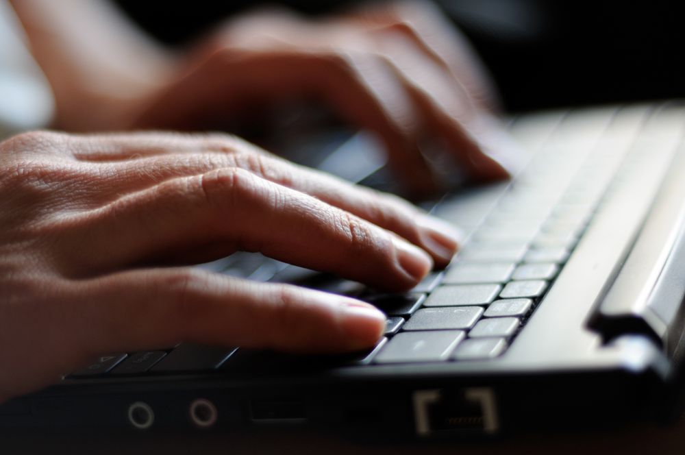 Close up of hands typing on keyboard of laptop