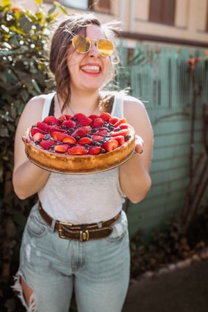 cheerful woman holding a delicious strawberry pie