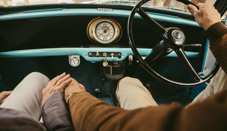 Close up of a mature couple holding hands while driving a car