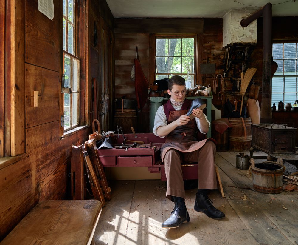 Costumed interpreter at work at the shoeshop at Old Sturbridge Village, Sturbridge, Massachusetts