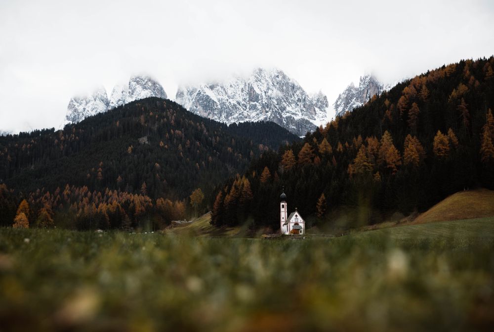 Small church on cliff near forest and mountains