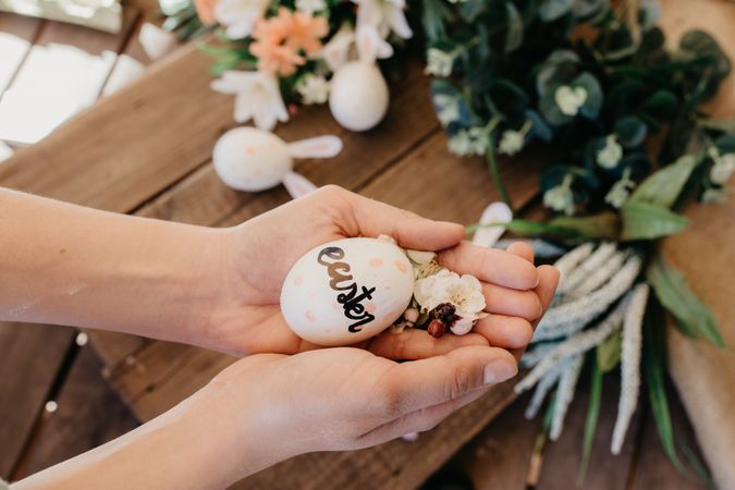 young woman holding an easter egg painted by children with flowers