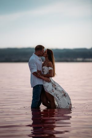 Side view of adorable couple embracing into an amazing beach with pink water