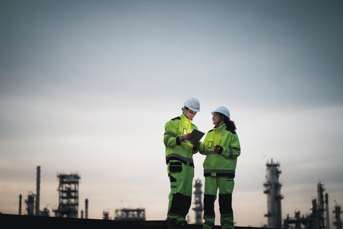 Engineer worker watching work monitor on digital tablet at refinery factory at night