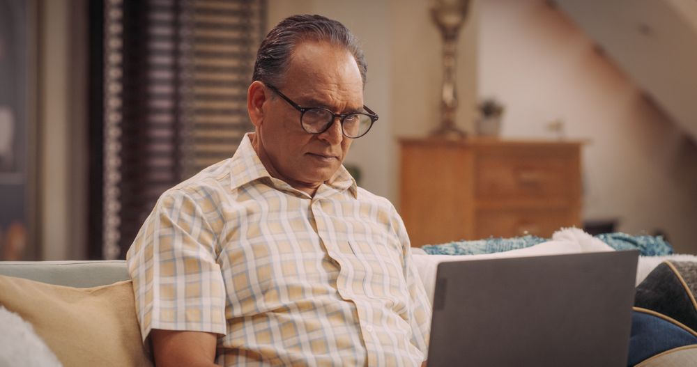 Indian Man Using Laptop At Home