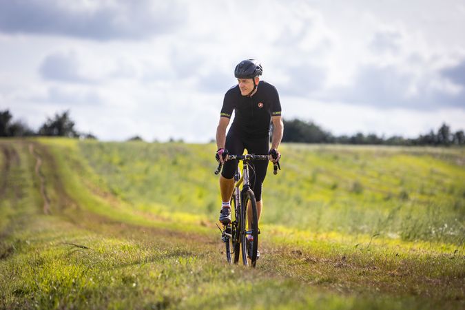 Older man riding bicycle in field