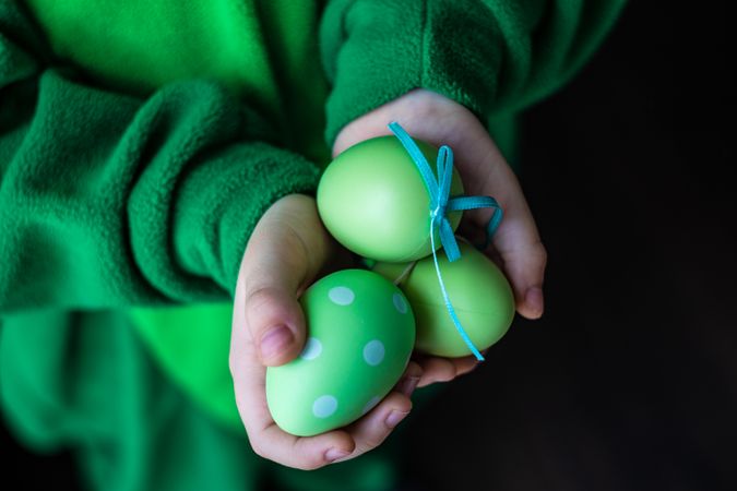Hands holding green decorative eggs