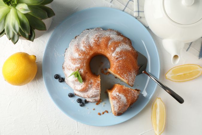 Cake with powdered sugar, blueberry and mint on plain background, top view